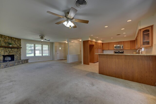 906 Carlee Dr, Brenham, TX 77833 - kitchen with stainless steel microwave, light colored carpet, a peninsula, glass insert cabinets, and brown cabinetry