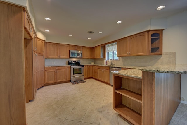 906 Carlee Dr, Brenham, TX 77833 - kitchen featuring stainless steel appliances, a peninsula, light stone counters, decorative backsplash, and recessed lighting