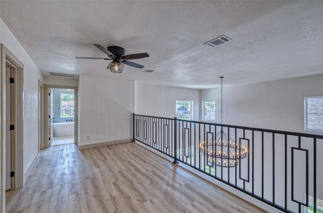 6 Rio Seco Dr, Uvalde, TX 78801 - empty room featuring a chandelier, wood finished floors, a textured ceiling, a ceiling fan, and plenty of natural light