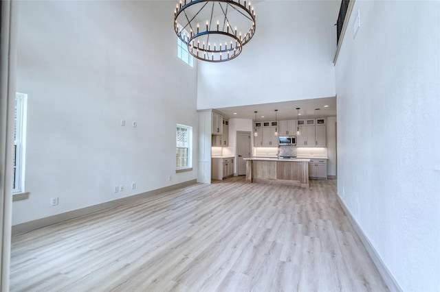 6 Rio Seco Dr, Uvalde, TX 78801 - unfurnished living room featuring a high ceiling, light wood finished floors, a chandelier, and plenty of natural light