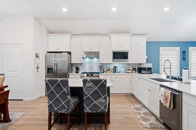 4236 Waterlily Spring Way, Porter, TX 77365 - kitchen with stainless steel appliances, a sink, tasteful backsplash, light wood-style floors, and a kitchen bar