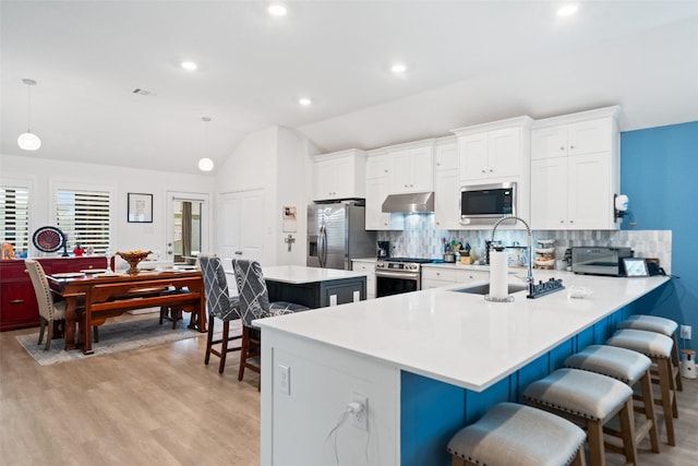 4236 Waterlily Spring Way, Porter, TX 77365 - kitchen featuring appliances with stainless steel finishes, a sink, under cabinet range hood, a breakfast bar, and light wood finished floors