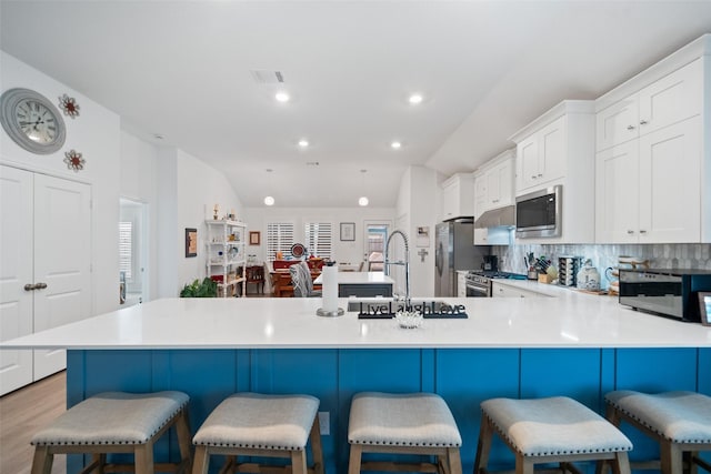4236 Waterlily Spring Way, Porter, TX 77365 - kitchen with appliances with stainless steel finishes, lofted ceiling, tasteful backsplash, light countertops, and white cabinetry