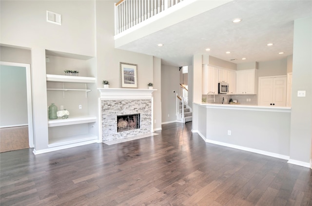 19927 Maple Village Dr, Cypress, TX 77433 - unfurnished living room with built in features, a high end fireplace, dark wood finished floors, stairs, and baseboards