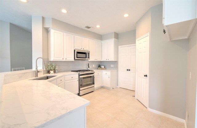19927 Maple Village Dr, Cypress, TX 77433 - kitchen featuring appliances with stainless steel finishes, a sink, light stone counters, backsplash, and white cabinets
