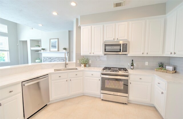 19927 Maple Village Dr, Cypress, TX 77433 - kitchen with appliances with stainless steel finishes, tasteful backsplash, white cabinetry, a sink, and recessed lighting