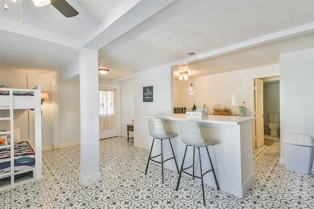 1513 19th St, Galveston, TX 77550 - kitchen featuring a kitchen bar, ceiling fan, baseboards, decorative light fixtures, and light countertops