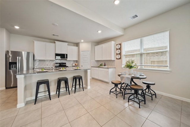 6531 Cody Mountain Trl, Richmond, TX 77407 - kitchen with stainless steel appliances, decorative backsplash, a breakfast bar area, a center island with sink, and white cabinets