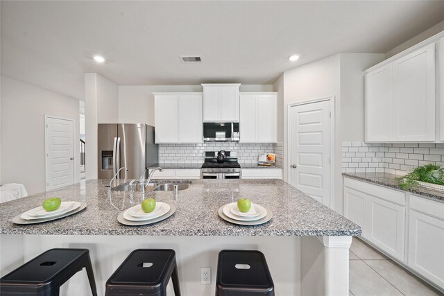 6531 Cody Mountain Trl, Richmond, TX 77407 - kitchen with stainless steel appliances, a sink, a breakfast bar, white cabinets, and recessed lighting