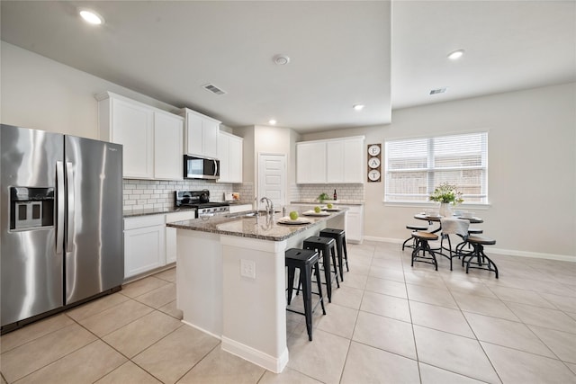 6531 Cody Mountain Trl, Richmond, TX 77407 - kitchen featuring appliances with stainless steel finishes, a kitchen breakfast bar, decorative backsplash, an island with sink, and recessed lighting