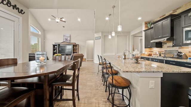 5903 Red River Dr, Manvel, TX 77578 - kitchen featuring tasteful backsplash, a kitchen breakfast bar, light stone countertops, a kitchen island with sink, and light wood-style floors