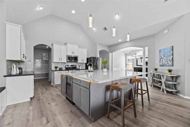 10506 Star Thistle Ct, Cypress, TX 77433 - kitchen featuring appliances with stainless steel finishes, arched walkways, beverage cooler, a chandelier, and backsplash