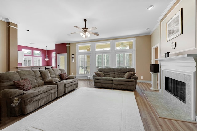 2005 Mistwood Ct, Pearland, TX 77584 - living room featuring ceiling fan, light wood-style flooring, a tile fireplace, ornamental molding, and plenty of natural light