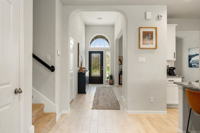 77 Indian Wells Dr, Manvel, TX 77578 - foyer entrance with arched walkways, baseboards, stairs, light wood finished floors, and a high ceiling