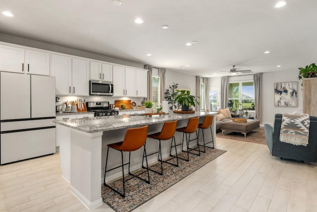 77 Indian Wells Dr, Manvel, TX 77578 - kitchen featuring stainless steel appliances, recessed lighting, white cabinets, and light wood-type flooring