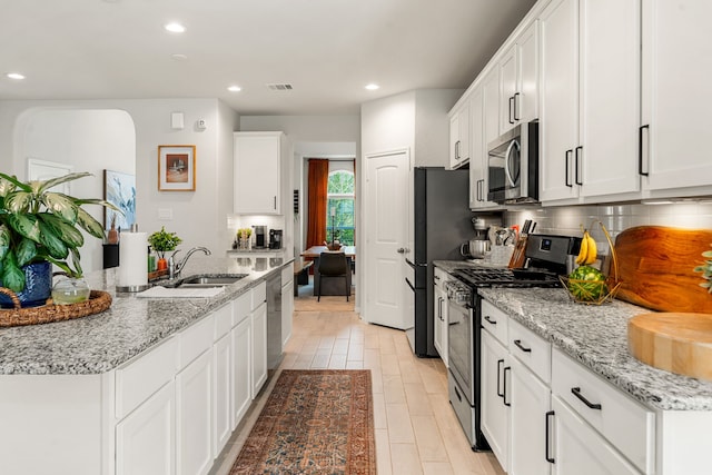 77 Indian Wells Dr, Manvel, TX 77578 - kitchen with appliances with stainless steel finishes, a sink, tasteful backsplash, white cabinetry, and recessed lighting