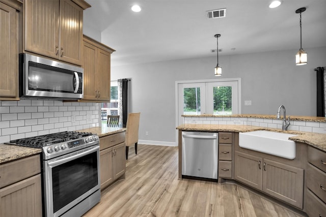 4142 Longhorn Dr, Cleveland, TX 77328 - kitchen with appliances with stainless steel finishes, tasteful backsplash, light wood finished floors, pendant lighting, and recessed lighting