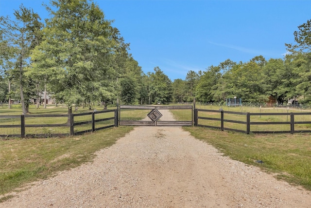4142 Longhorn Dr, Cleveland, TX 77328 - view of dirt / gravel driveway with a gate and a rural view