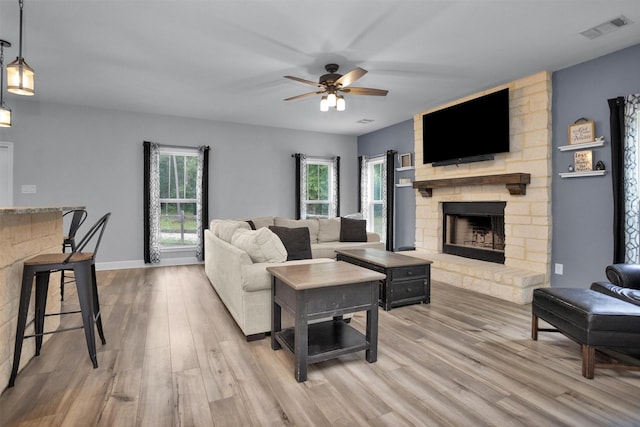 4142 Longhorn Dr, Cleveland, TX 77328 - living room featuring a stone fireplace, light wood-style flooring, and ceiling fan