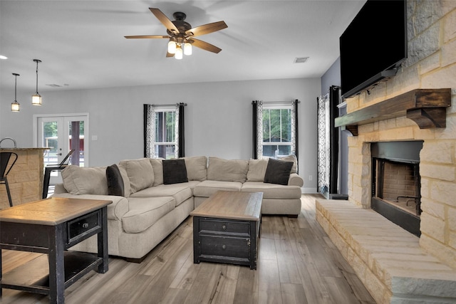 4142 Longhorn Dr, Cleveland, TX 77328 - living room featuring a stone fireplace, wood finished floors, a ceiling fan, and french doors