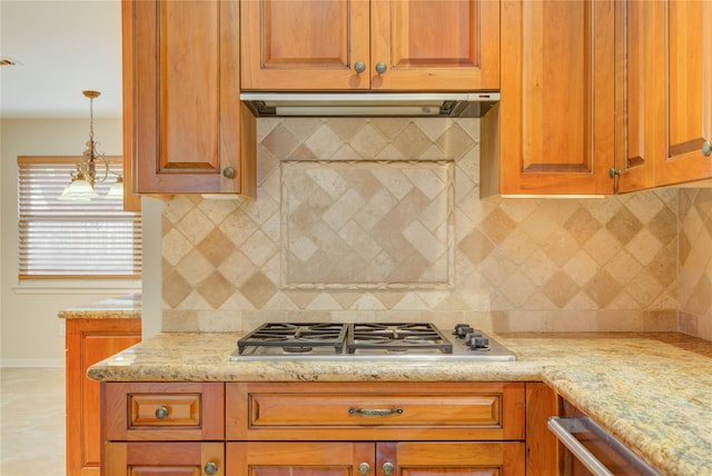 5311 Graystone Ln, Houston, TX 77069 - kitchen with ventilation hood, stainless steel gas cooktop, baseboards, light stone countertops, and brown cabinetry