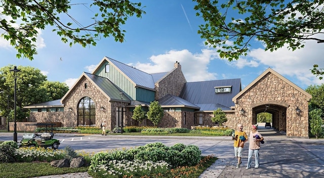 10003 Monarch Landing Cv, Willis, TX 77318 - view of front of property featuring a standing seam roof, stone siding, a chimney, and metal roof