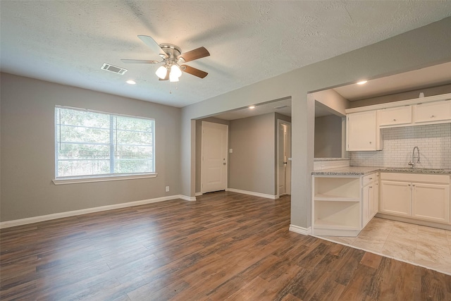 3915 Florinda St, Houston, TX 77021 - kitchen featuring open shelves, decorative backsplash, a ceiling fan, white cabinetry, and a textured ceiling