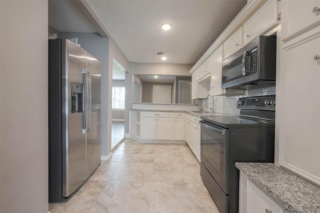3915 Florinda St, Houston, TX 77021 - kitchen featuring stainless steel appliances, a sink, light stone countertops, white cabinets, and backsplash