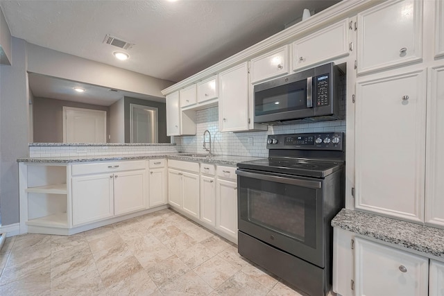 3915 Florinda St, Houston, TX 77021 - kitchen featuring black range with electric stovetop, stainless steel microwave, a sink, and white cabinets