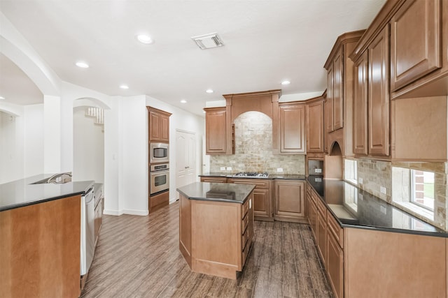 22011 Twinkle Sky Ct, Cypress, TX 77433 - kitchen with appliances with stainless steel finishes, dark countertops, a center island, dark wood-style floors, and arched walkways