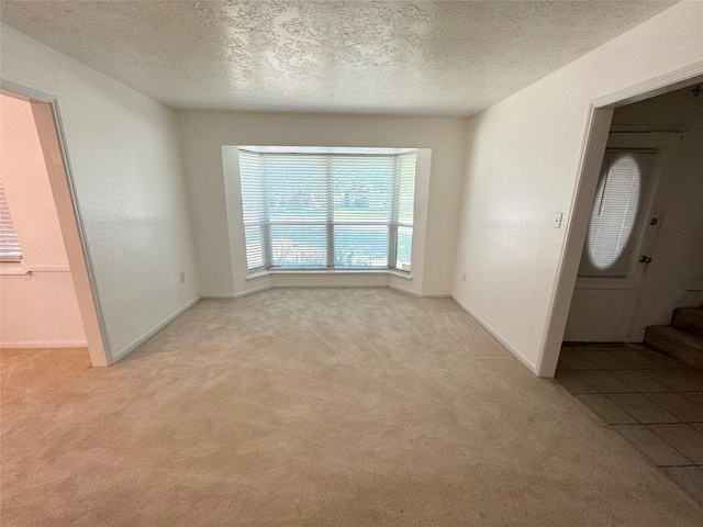 28811 Enchanted Dr, Shenandoah, TX 77381 - unfurnished room with light colored carpet, a textured ceiling, baseboards, and stairway
