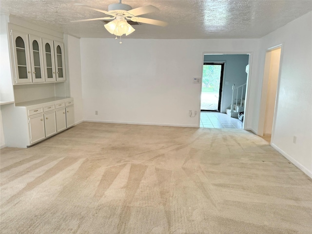 28811 Enchanted Dr, Shenandoah, TX 77381 - unfurnished living room with a textured ceiling, light carpet, a ceiling fan, and baseboards