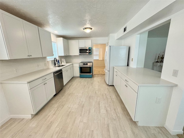 28811 Enchanted Dr, Shenandoah, TX 77381 - kitchen with appliances with stainless steel finishes, a sink, light wood-type flooring, a textured ceiling, and decorative backsplash