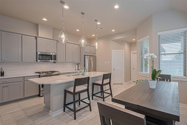 24227 Tallgrass Meadow Trl, Katy, TX 77493 - kitchen featuring appliances with stainless steel finishes, gray cabinetry, a sink, decorative backsplash, and an island with sink