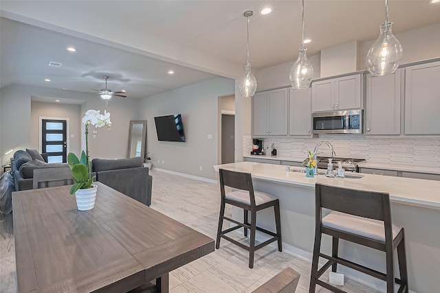 24227 Tallgrass Meadow Trl, Katy, TX 77493 - kitchen featuring stainless steel microwave, light countertops, decorative backsplash, recessed lighting, and gray cabinetry