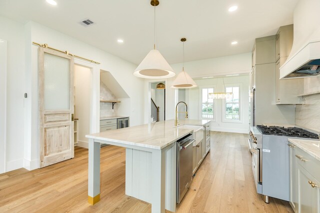 714 Vista Bella, Galveston, TX 77554 - kitchen with appliances with stainless steel finishes, premium range hood, light wood-style flooring, a kitchen island with sink, and a sink