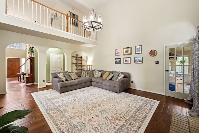 16418 Willowpark Dr, Tomball, TX 77377 - living room with arched walkways, a towering ceiling, dark wood-type flooring, a chandelier, and baseboards