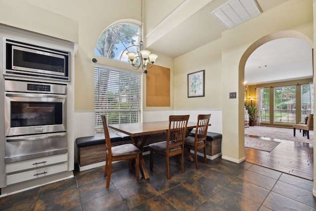 16418 Willowpark Dr, Tomball, TX 77377 - dining space featuring arched walkways, a chandelier, and wainscoting