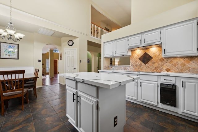 16418 Willowpark Dr, Tomball, TX 77377 - kitchen with arched walkways, a chandelier, decorative backsplash, a kitchen island, and pendant lighting