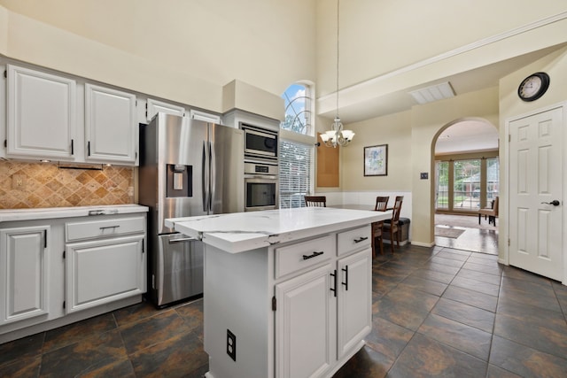 16418 Willowpark Dr, Tomball, TX 77377 - kitchen featuring appliances with stainless steel finishes, arched walkways, a center island, backsplash, and hanging light fixtures