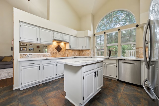 16418 Willowpark Dr, Tomball, TX 77377 - kitchen featuring stainless steel appliances, high vaulted ceiling, stone tile floors, a center island, and white cabinets
