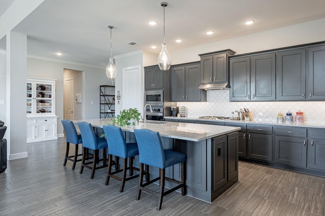 30411 Indigo Falls Dr, Brookshire, TX 77423 - kitchen featuring backsplash, a kitchen island with sink, dark wood-style floors, light stone counters, and ornamental molding