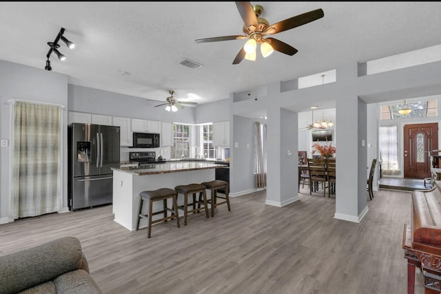 5418 Forest Springs Dr, Houston, TX 77339 - kitchen with black appliances, white cabinetry, a center island, a ceiling fan, and open floor plan