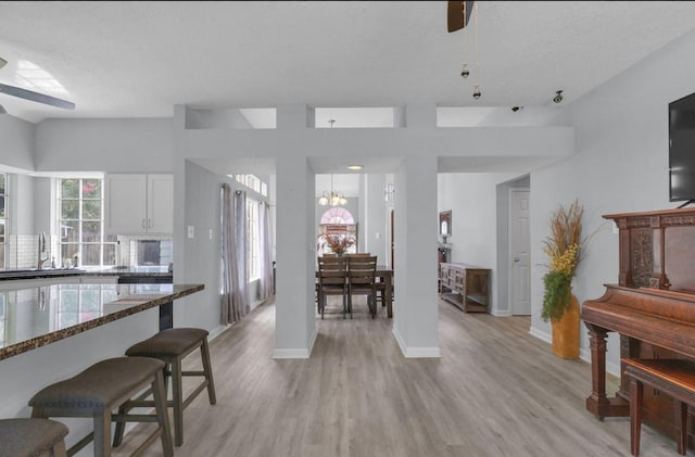 5418 Forest Springs Dr, Houston, TX 77339 - kitchen featuring ceiling fan, a kitchen bar, dark stone countertops, light wood-style flooring, and white cabinetry