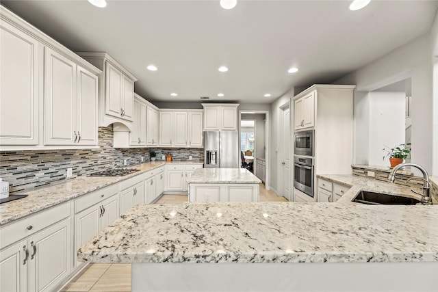 6 Volerran Path Ln, Missouri City, TX 77459 - kitchen with appliances with stainless steel finishes, a sink, backsplash, light stone counters, and recessed lighting