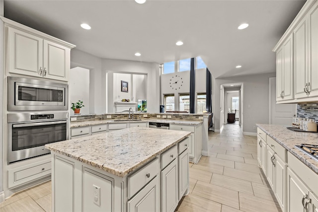 6 Volerran Path Ln, Missouri City, TX 77459 - kitchen with appliances with stainless steel finishes, a sink, a peninsula, a kitchen island, and recessed lighting