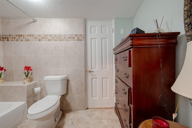2087 Rd 5210, Cleveland, TX 77327 - full bathroom featuring a bath, toilet, tile walls, a textured ceiling, and tile patterned floors