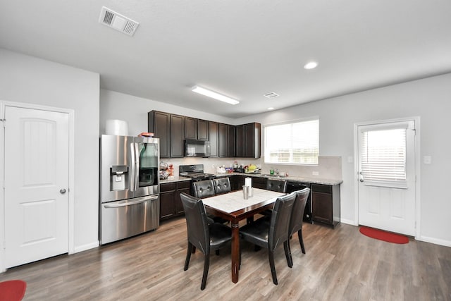 18510 Snowy River Ln, Katy, TX 77084 - kitchen with stainless steel refrigerator with ice dispenser, black microwave, stove, wood finished floors, and recessed lighting