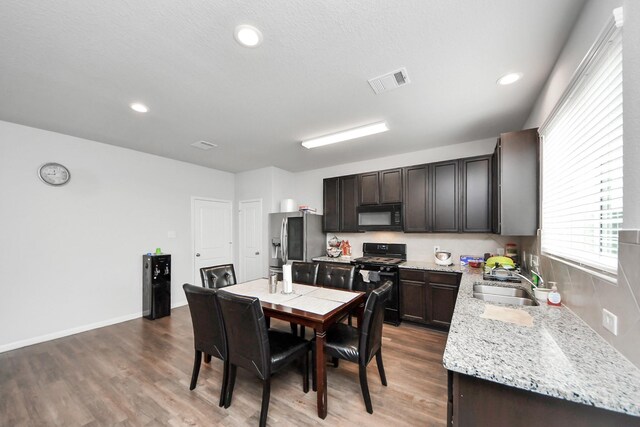 18510 Snowy River Ln, Katy, TX 77084 - kitchen with black microwave, range with gas cooktop, stainless steel fridge with ice dispenser, a sink, and wood finished floors