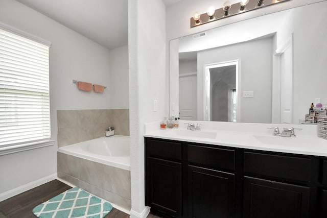 18510 Snowy River Ln, Katy, TX 77084 - bathroom featuring double vanity, a bath, wood finished floors, and baseboards